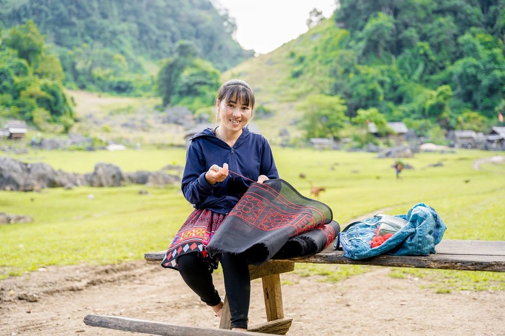 Hmong woman with her favorite job of embroidering dresses